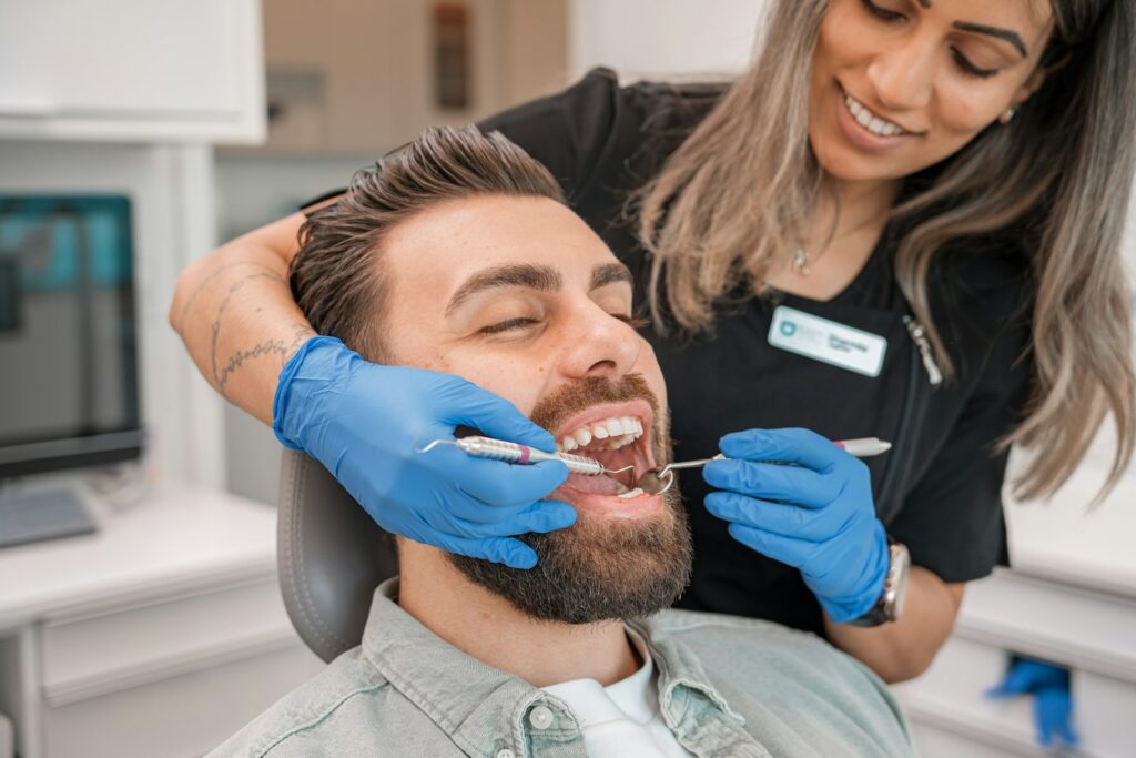 Dentist in blue gloves examining a patient's teeth