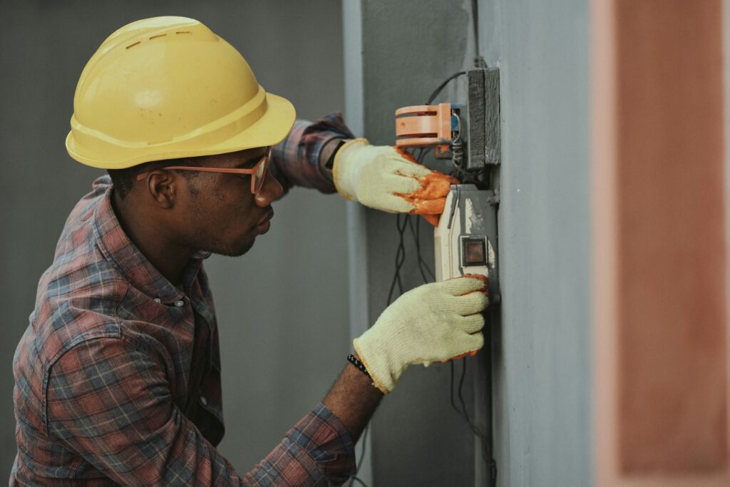 Technician in a yellow hard hat installing wiring