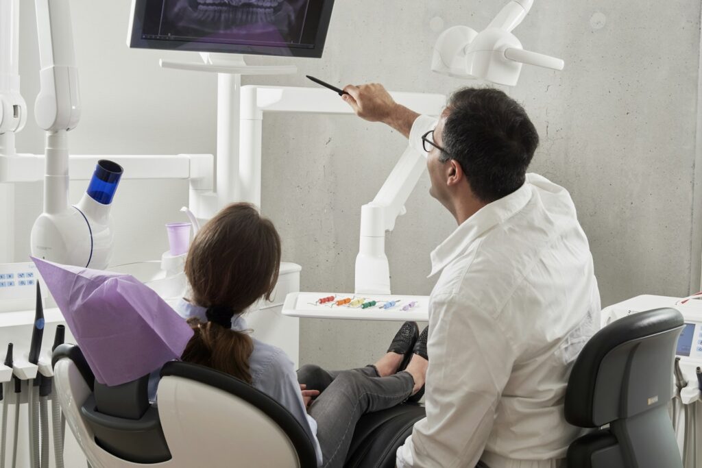 Dentist in a white shirt holding a pen during a consultation